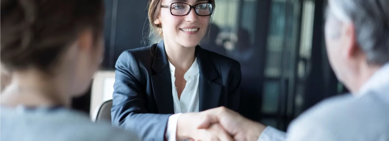 A businesswoman shaking hands with a married couple.